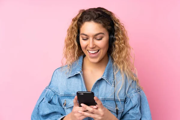 Jovem Loira Com Cabelo Encaracolado Isolado Fundo Rosa Ouvir Música — Fotografia de Stock