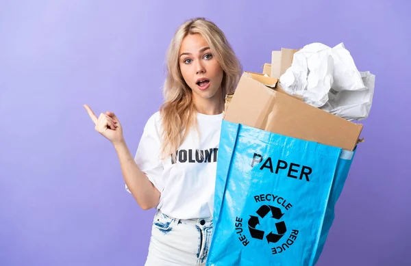 Młoda Rosjanka Trzymająca Torbę Papierem Recyklingu Odizolowaną Fioletowym Tle Zaskoczona — Zdjęcie stockowe