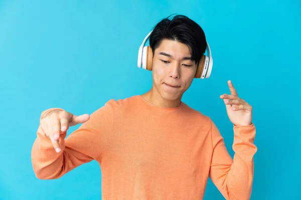 Молодой Китаец Изолирован Синем Фоне Слушает Музыку Танцует — стоковое фото