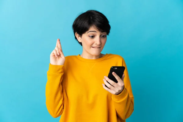 Frau Mit Kurzen Haaren Isoliert Auf Blauem Hintergrund Mit Handy — Stockfoto