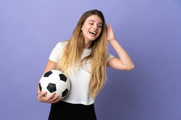 Młoda Blondynka Piłkarz Kobieta Odizolowany Fioletowym Tle Słuchając Czegoś Przez — Zdjęcie stockowe