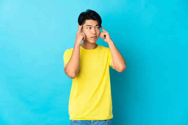Jeune Homme Chinois Isolé Sur Fond Bleu Ayant Des Doutes — Photo