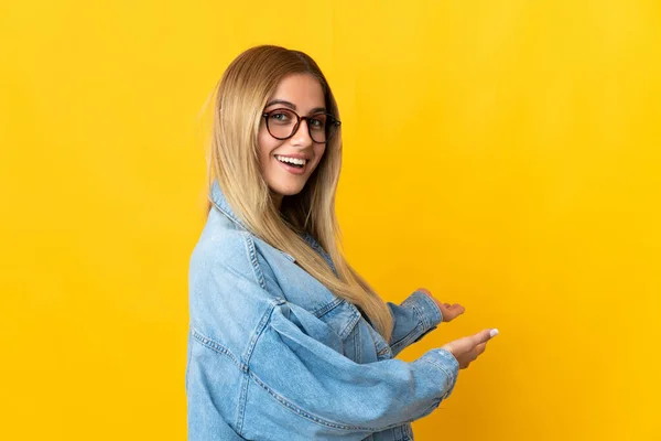 Jonge Blonde Vrouw Geïsoleerd Gele Achtergrond Uitstrekken Handen Naar Zijkant — Stockfoto