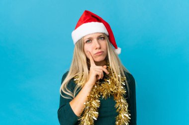 Mavi arka planda izole edilmiş, Noel şapkalı bir kadın.