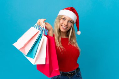 Noel şapkalı bir kadın mavi arka planda izole edilmiş mutlu bir şey alacak.