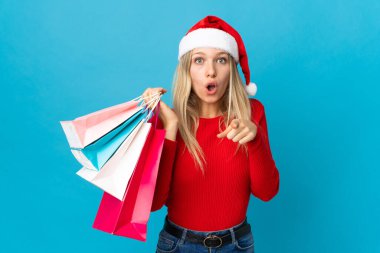 Noel şapkalı kadın mavi arka planda izole edilmiş bir şey alacak.