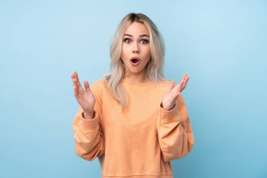 Yüzü sürpriz bir ifadeyle mavi arka planda kalan genç bir kız.