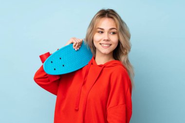 Genç Rus kız mavi arka planda paten kayarak izole edilmiş.