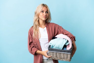Elinde çamaşır sepeti olan genç bir Rus kadın mavi arka planda izole edilmiş ve yukarı bakıyor.