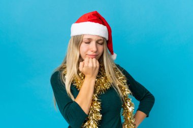 Mavi arka planda izole edilmiş Noel şapkalı kadının şüpheleri var.