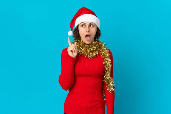 英語の女の子とともにクリスマスの帽子隔離された上に青の背景考え方指を指す — ストック写真