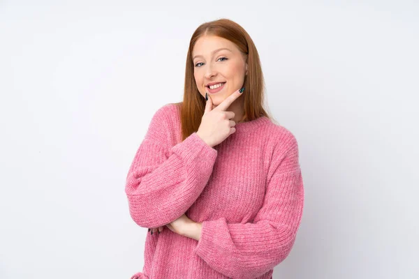 年轻的红头发女人 穿着粉色毛衣 背对孤立的白色背景 面带微笑 — 图库照片