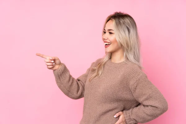 Chica Rubia Adolescente Con Suéter Sobre Fondo Rosa Aislado Apuntando — Foto de Stock