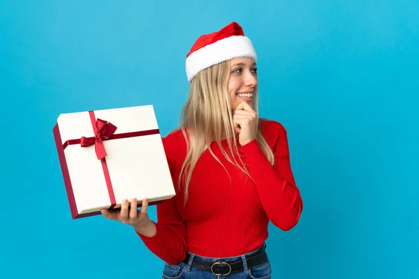 Kvinna Med Jul Hatt Hålla Present Isolerad Blå Bakgrund Tänker — Stockfoto