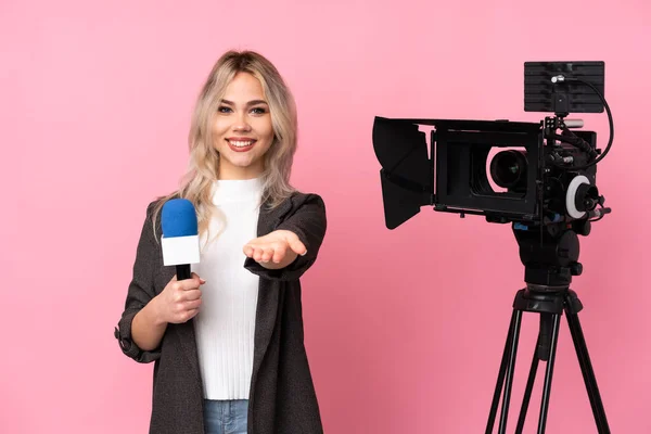 Reporter woman holding a microphone and reporting news over isolated pink background holding copyspace imaginary on the palm to insert an ad