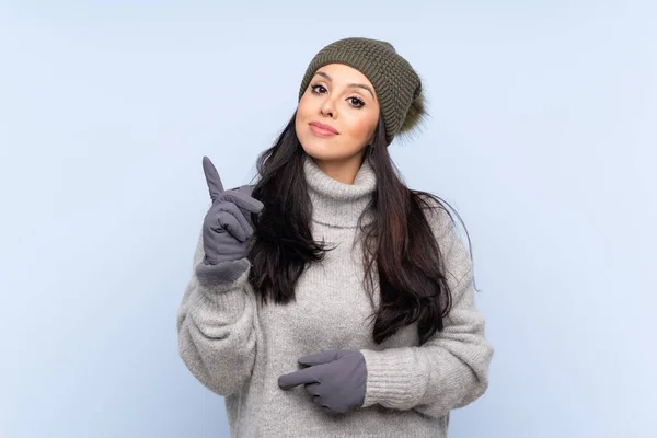 Jeune Colombienne Avec Chapeau Hiver Sur Fond Bleu Isolé Pointant — Photo