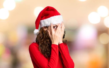 İzole edilmiş kırmızı arka planda Noel şapkası takan kız.