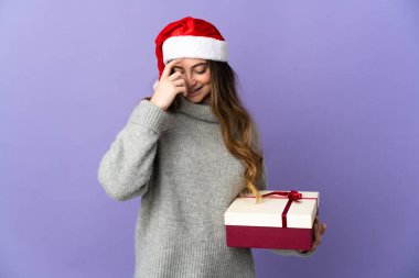 Noel şapkalı kız elinde hediyeyle beyaz arka planda beş parmaklı sayım yapıyor.