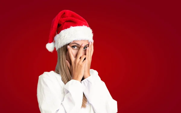 Девушка Рождественской Шляпе Изолированном Фоне Закрывает Глаза Смотрит Сквозь Пальцы — стоковое фото