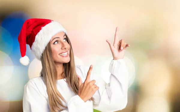 Girl Christmas Hat Pointing Index Finger Great Idea Unfocused Background — ストック写真