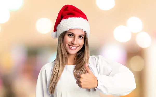 Девушка Рождественской Шляпе Подает Большой Палец Вверх Жестом Несосредоточенном Фоне — стоковое фото