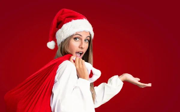 クリスマス休暇で若いですブロンド女性ピックアップバッグのフルプレゼント上の隔離された赤の背景 — ストック写真