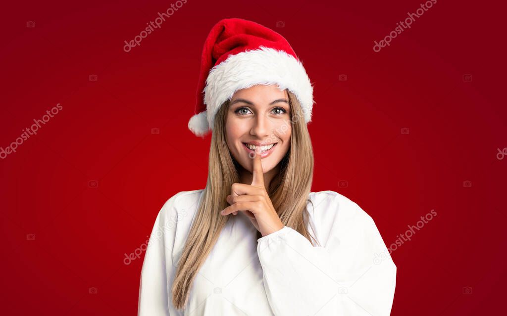 Girl with christmas hat over isolated background doing silence gesture
