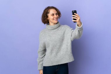 Genç İngiliz bisikletçi kadın, beyaz arka planda izole edilmiş mutlu ve gülümseyen ağızlarını eliyle kapatıyor.