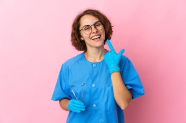 Genç İngiliz bisikletçi kadın, beyaz arka planda izole edilmiş mutlu ve gülümseyen ağızlarını eliyle kapatıyor.