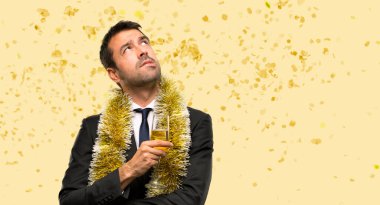 Şampanyalı bir adam yeni yılı kutluyor ciddi bir yüzle bir partide konfetiye bakıyor.