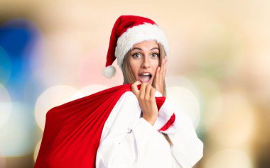 Genç sarışın kadın, Noel 'de bir çanta dolusu hediyeyi dikkatsiz bir şekilde alıyor.