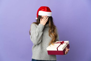 Noel şapkalı kız elinde hediyeyle beyaz arka planda beş parmaklı sayım yapıyor.