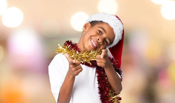 戴着圣诞礼帽的非裔美国男孩带着自信的表情对着你指指点点 而不是模糊的背景 — 图库照片