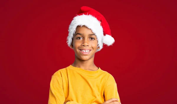 アフリカ系アメリカ人男の子とともにクリスマス帽子以上赤背景 — ストック写真