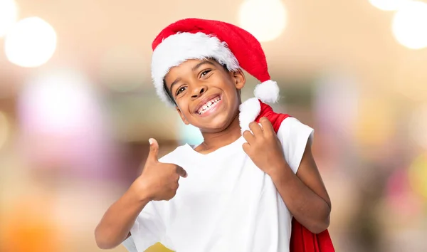Afroamerykanin Chłopiec Świątecznym Kapeluszu Biorąc Torbę Prezentami Rozmytym Tle — Zdjęcie stockowe