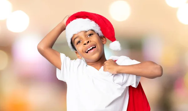 戴着圣诞礼帽 提着装有礼物的袋子 背景模糊的非裔美国男孩 — 图库照片
