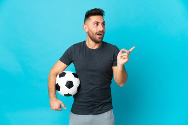 Futbolcu mavi arka planda izole edilmiş bir şekilde parmağını kaldırırken çözümü anlamaya çalışıyor.