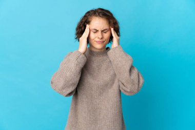 Genç İngiliz kadın mavi arka planda baş ağrısı ile izole edildi.