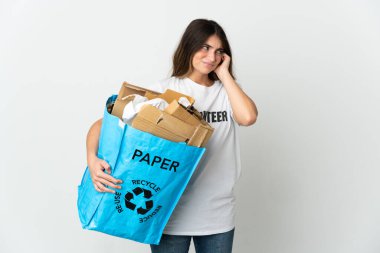 Elinde kağıt dolu bir geri dönüşüm çantası tutan genç bir kadın. Beyazların arka planında izole edilmiş ve kulaklarını tıkayan.