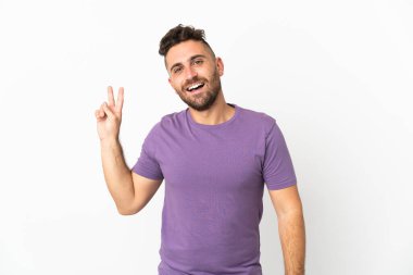 Beyaz arka planda izole edilmiş beyaz bir adam gülümsüyor ve zafer işareti gösteriyor.