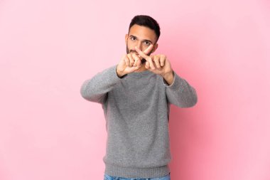 Pembe arka planda izole edilmiş genç beyaz adam bir hareketi durdurmak için eliyle jest yapıyor.