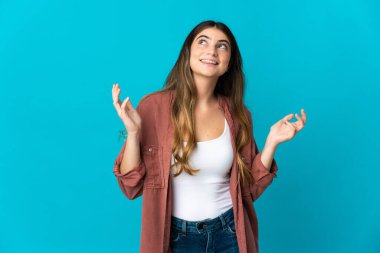 Mavi arka planda izole edilmiş genç beyaz kadın çok gülümsüyor.