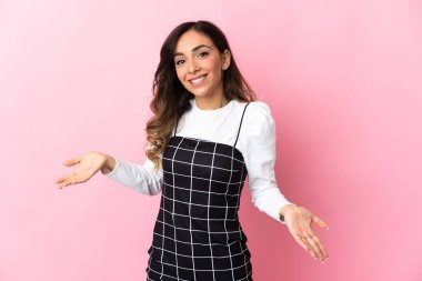 Pembe arka planda izole edilmiş genç beyaz kadın mutlu ve gülümsüyor.