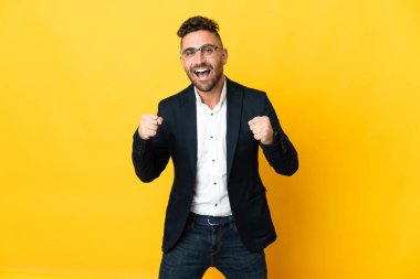 İş adamı sarı arka plan üzerinde galibiyeti kutluyor.