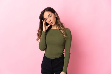 Pembe arka planda izole edilmiş, başı ağrıyan beyaz bir kadın.