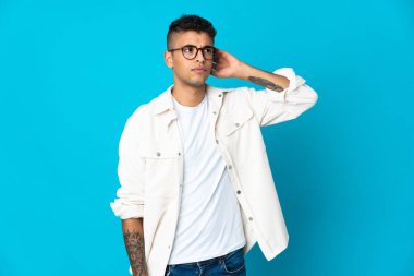 Mavi arka planda izole edilmiş genç Brezilyalı adamın şüpheleri var.