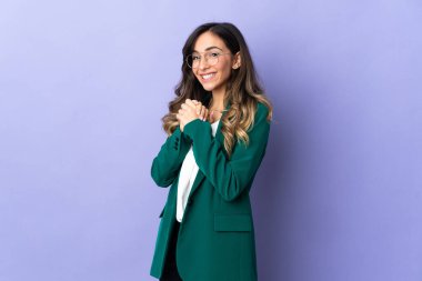 Mor arka planda izole edilmiş genç beyaz kadın gülüyor.