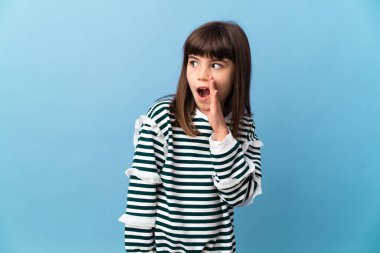 İzole edilmiş arka planda küçük bir kız yan tarafa bakarken sürpriz bir hareketle bir şeyler fısıldıyor.