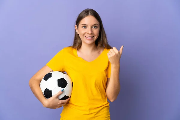 年轻的立陶宛女足球运动员被隔离在紫色背景下 指着侧面展示自己的产品 — 图库照片