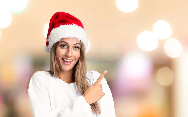 Odaklanmamış Arka Planda Noel Şapkası Takmış Bir Kız Parmağıyla Işaret — Stok fotoğraf